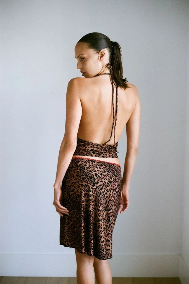 Woman wearing a leopard print top with thin straps against a plain background
