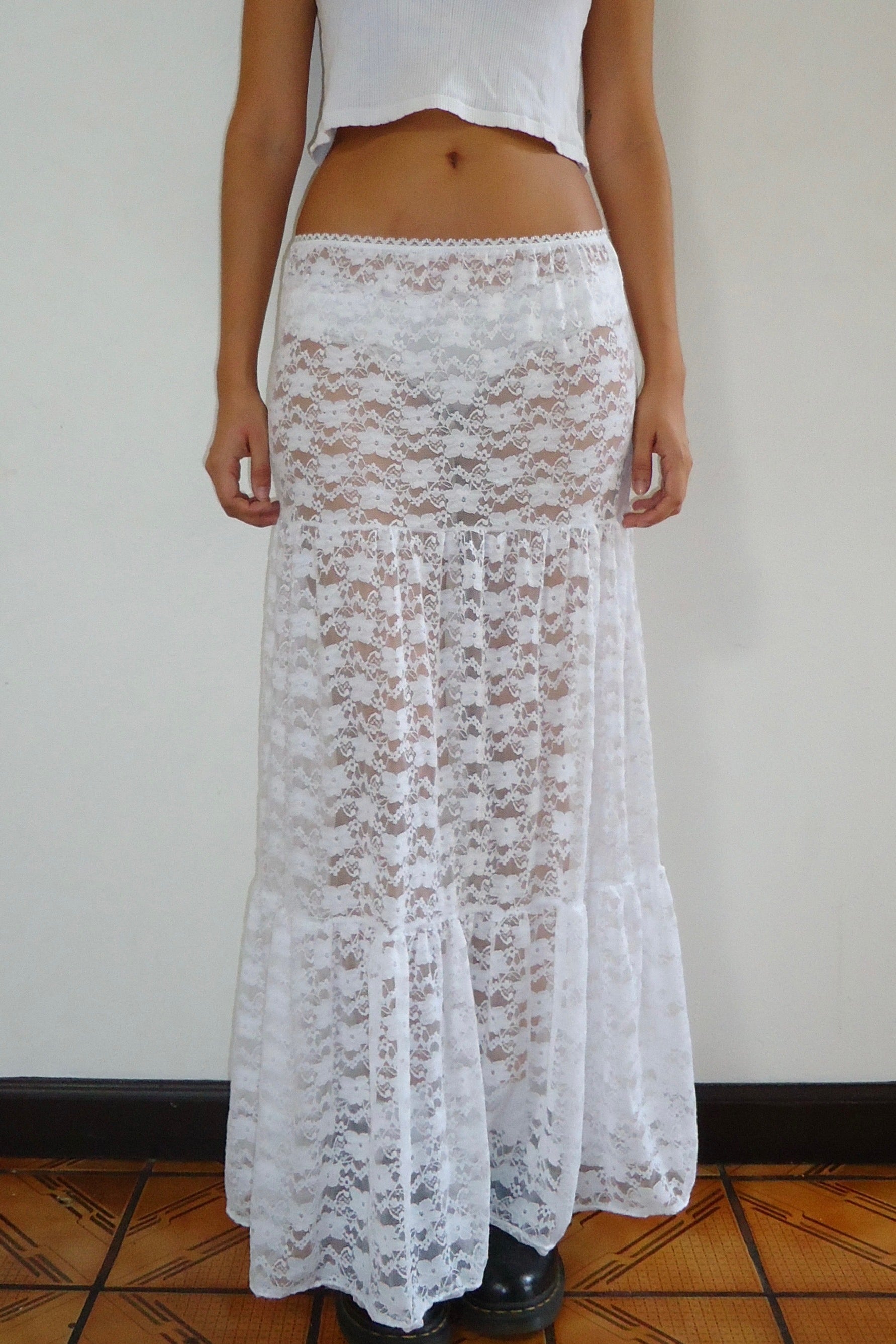 Person wearing a white lace maxi skirt on a plain background