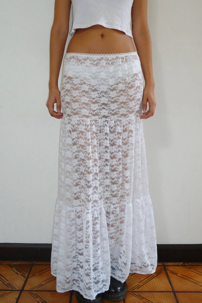 Person wearing a white lace maxi skirt on a plain background