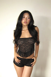 Woman wearing a black lace top and shorts against a plain background