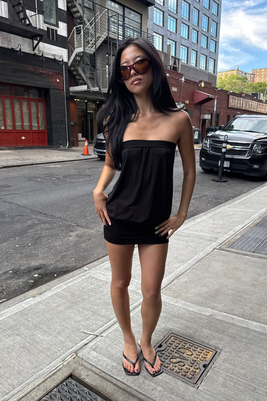 girl wearing a black slouchy mini strapless dress on the sidewalk in new york city