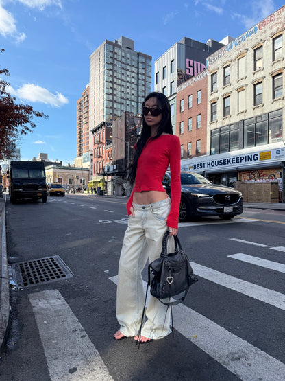 Person standing on a city street with buildings and cars in the background