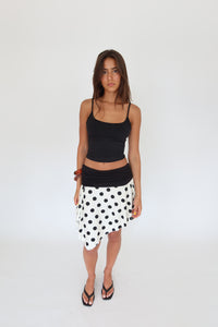 Woman wearing a black top and polka dot skirt on a white background