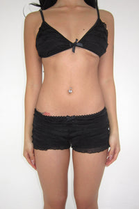 Person wearing a black bra and shorts set on a white background