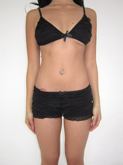 Person wearing a black bra and shorts set on a white background