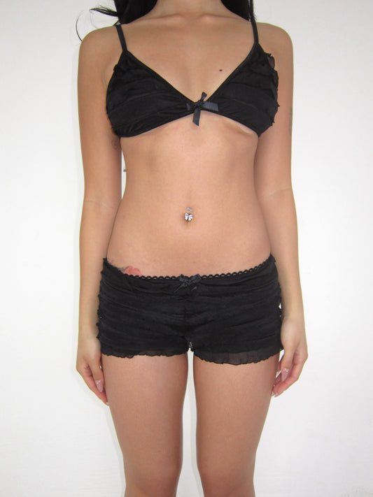 Person wearing a black bra and shorts set on a white background