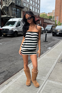 girl wearing strapless black and white striped strapless mini dress and tall ugg boots on the street on new york city