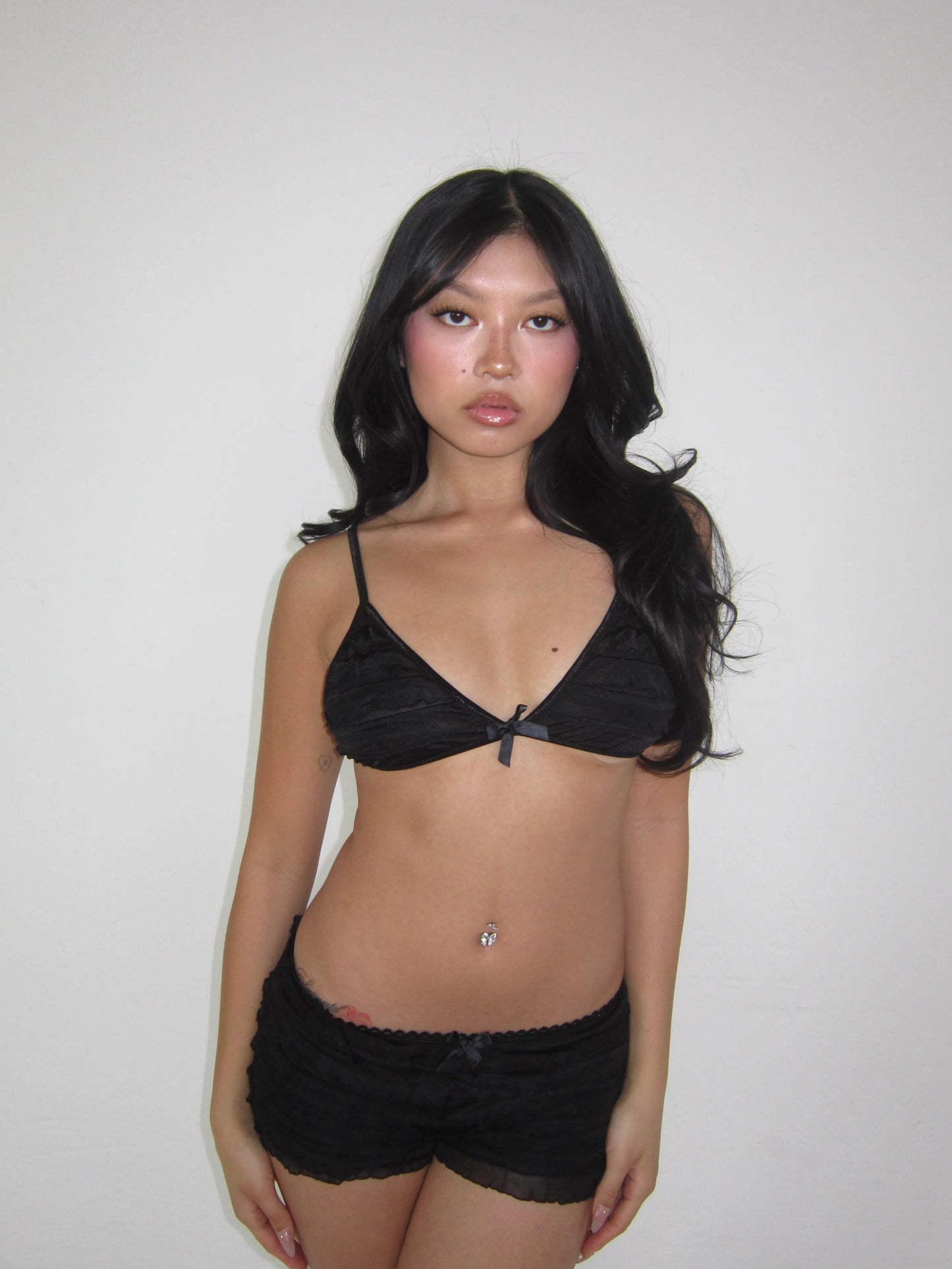 Woman wearing a black bra and shorts against a plain background