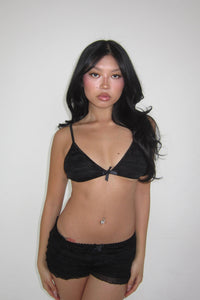 Woman wearing a black bra and shorts against a plain background