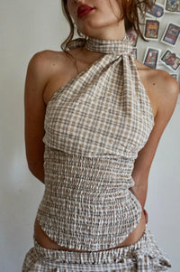 Woman wearing a plaid halter top against a neutral background