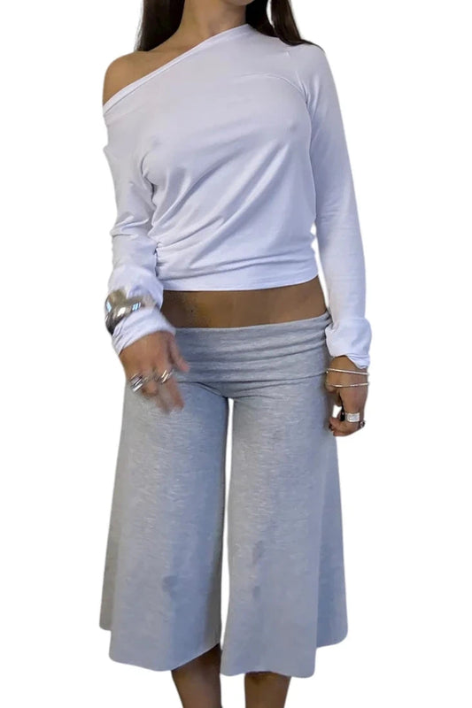 Woman wearing a white off-shoulder top and light gray foldover gauchos on a white background