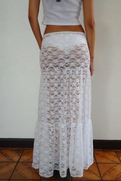 Person wearing a white lace maxi skirt on a plain background