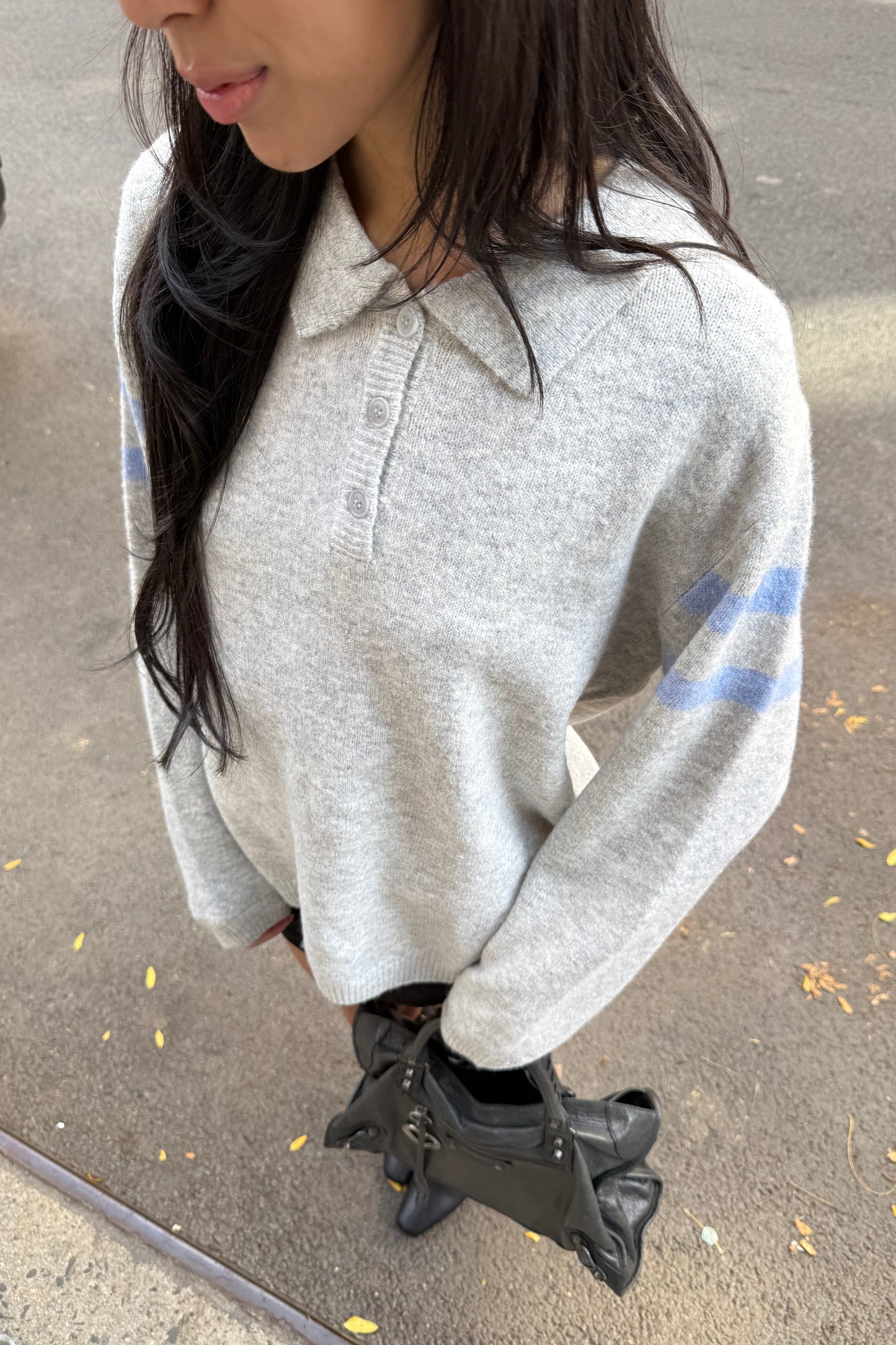 Person wearing a gray hoodie with a blue design, lying on a concrete surface.