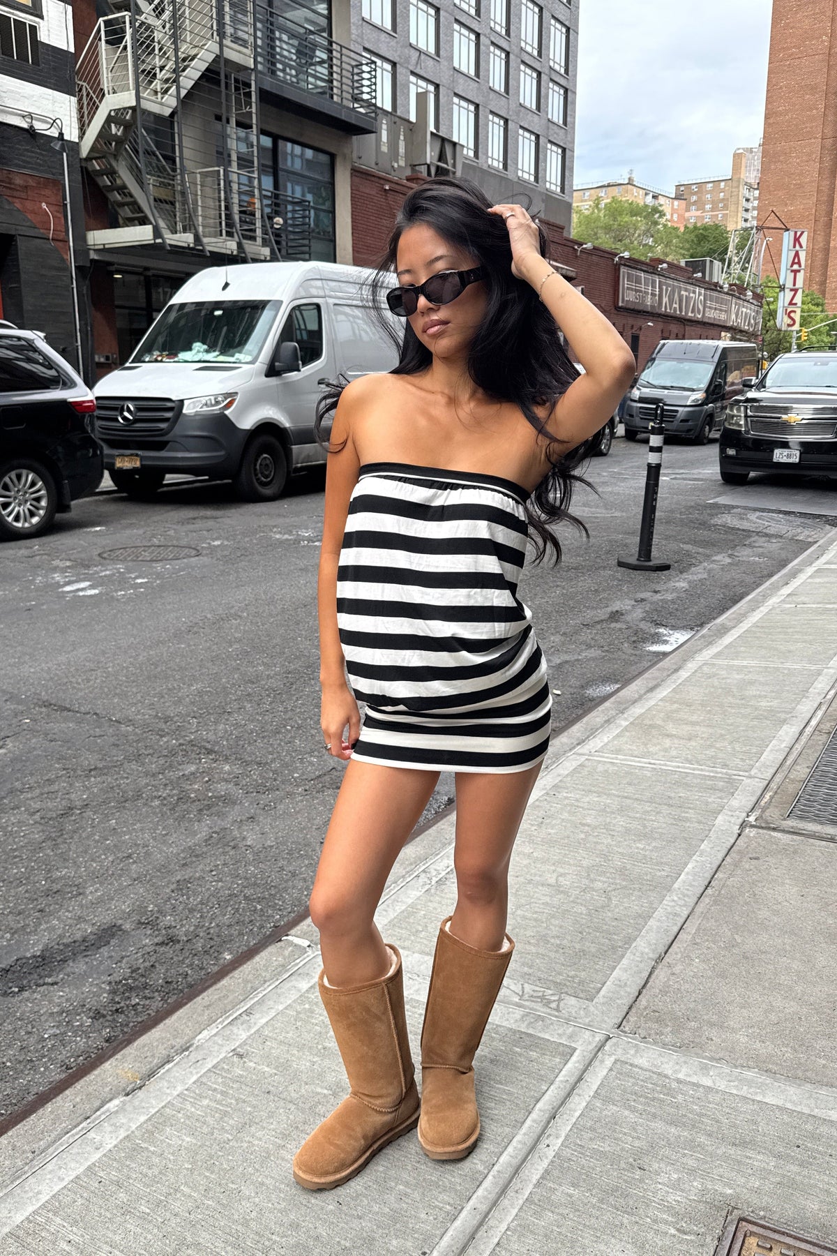 girl wearing strapless black and white striped strapless mini dress and tall ugg boots on the street on new york city