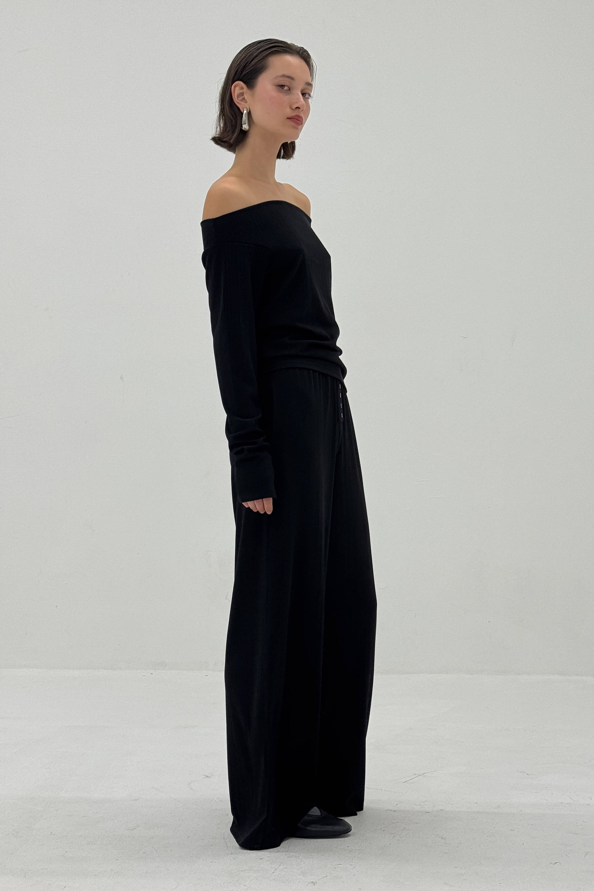 Woman wearing a black off-shoulder top against a white background