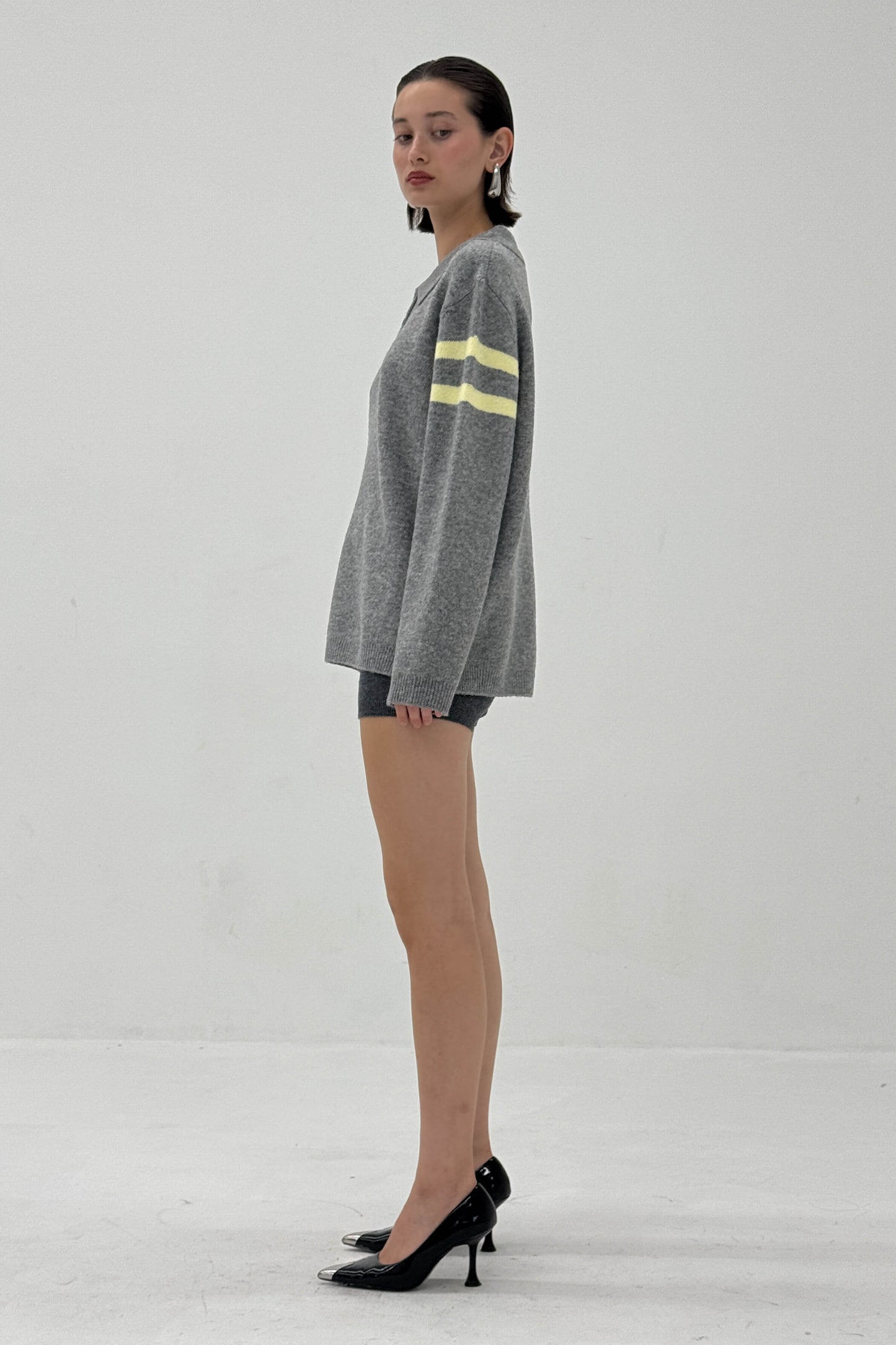 Woman wearing a gray sweater with yellow stripes on a white background
