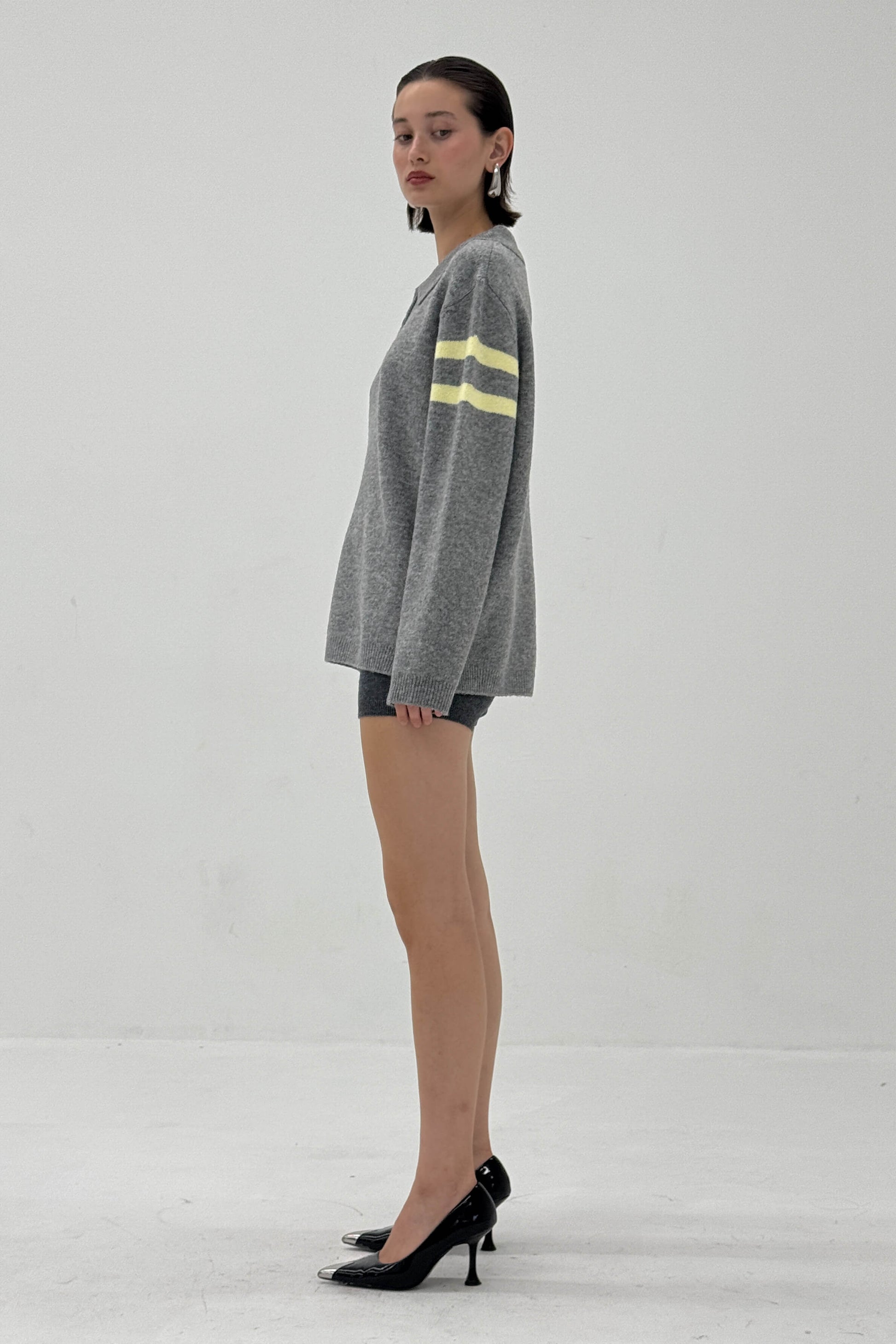 Woman wearing a gray sweater with yellow stripes on a white background