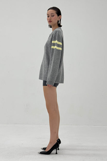 Woman wearing a gray sweater with yellow stripes on a white background