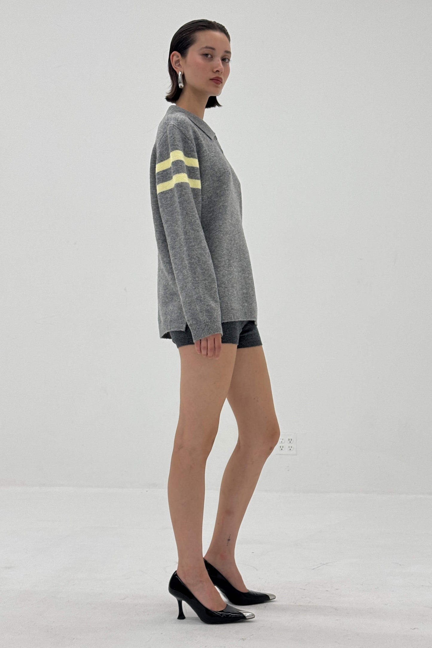 Woman wearing a gray sweater with yellow stripes on a white background