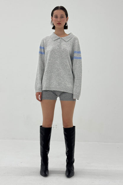 Person wearing a gray sweater with blue stripes, gray shorts, and black knee-high boots on a white background