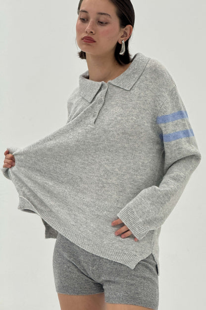 Woman wearing a gray sweater with blue stripes and matching shorts on a white background