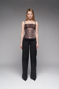 Woman wearing a leopard print top and black pants on a gray background