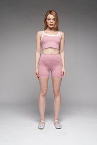 Woman wearing a pink athletic outfit on a gray background