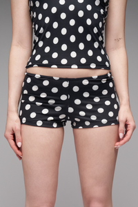 Person wearing black and white polka dot shorts on a gray background