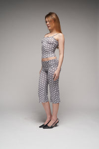 This image displays a stylish pair of dottie capris, characterized by a charming grey polka dot pattern. The capris are crafted from a soft, fold-over viscose jersey, adding a touch of comfort and elegance.