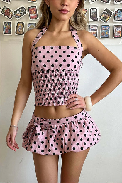 Woman wearing a pink polka dot outfit with a white background