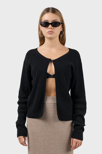 girl wearing a black ribbed knit cardigan with single button closure at the top and a bralette under